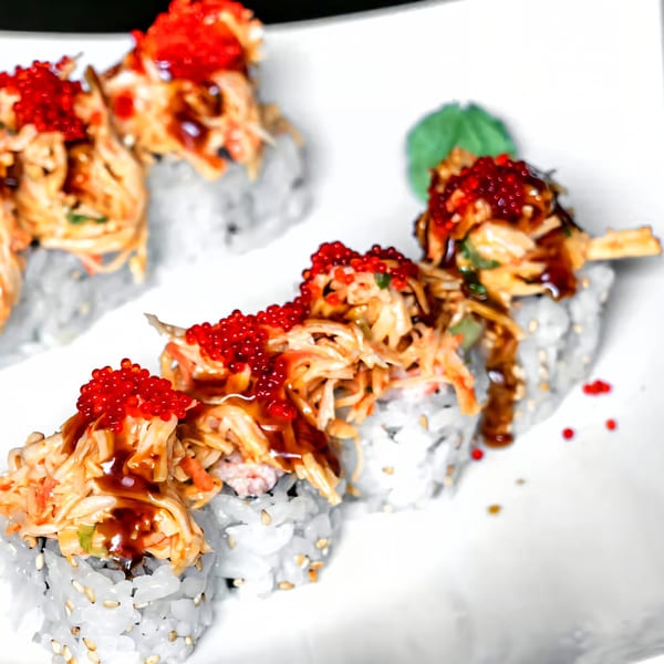 Agami Sushi's sushi rolls topped with shredded crab, red roe, and a dark sauce.
