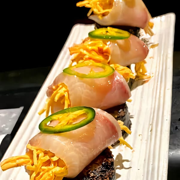 Agami Sushi's special rolls with fish, yellow strips, and green jalapeño slices on a white plate.