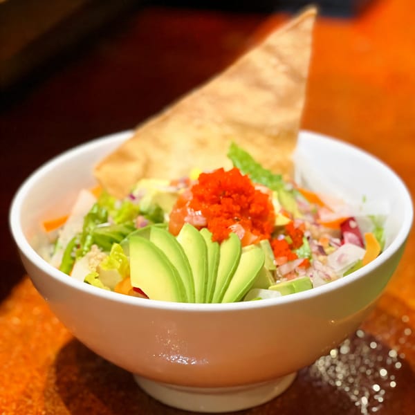 Agami Sushi's vibrant salad with avocado, red roe, and a crispy tortilla chip in a white bowl.